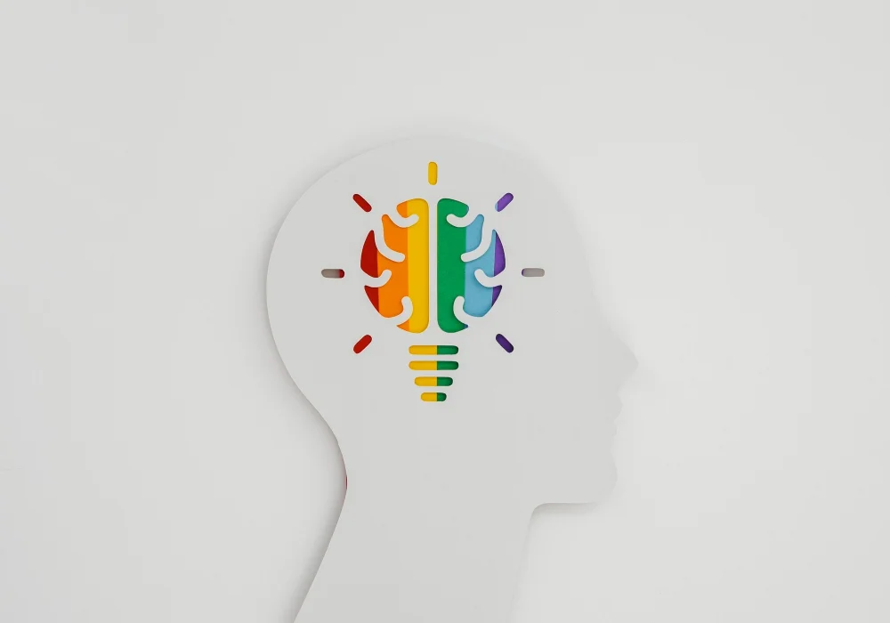 Illustrasjon av en hjerne i profil med fargerike seksjoner, som symboliserer mental helse og ADHD-forekomst hos barn og voksne.