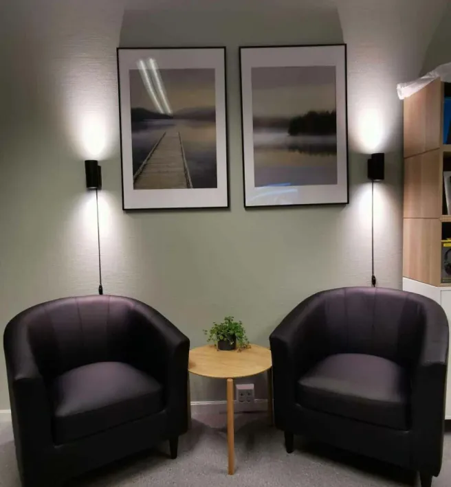 To komfortable stoler med bord og plante i et rolig kontormiljø, relevant for rus og avhengighetsmedisi rådgivning.