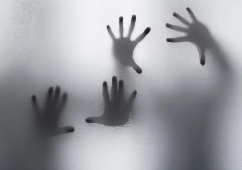 Skygger av hender bak frostet glass symboliserer hvordan stress og traumer kan påvirke psykose – et visuelt uttrykk for indre uro og psykisk kamp.