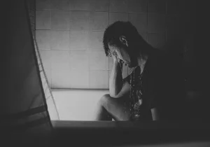 Person i dusjen med hodet lent mot hånden, et symbol på indre kamp og behov for behandling for angst og depresjon i en vanskelig livssituasjon.