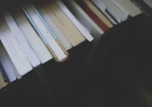 En samling bøker plassert tett sammen sett ovenfra, som symboliserer forbindelsen mellom litteratur og psykisk helse i utforskning og refleksjon.
