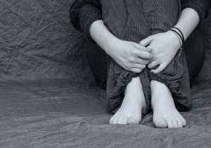 Svart-hvitt bilde av en person som sitter med armene rundt knærne, symboliserer følelsesmessig kamp og indre uro relatert til ADHD komorbiditet og psykisk helse.