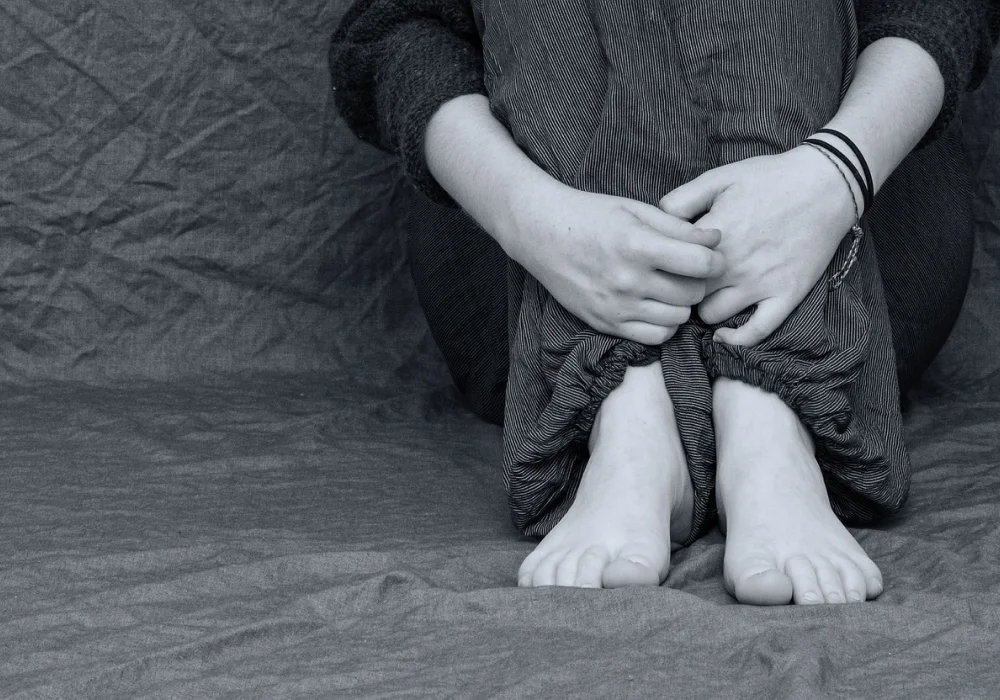 Svart-hvitt bilde av en person som sitter med armene rundt knærne, symboliserer følelsesmessig kamp og indre uro relatert til ADHD komorbiditet og psykisk helse.